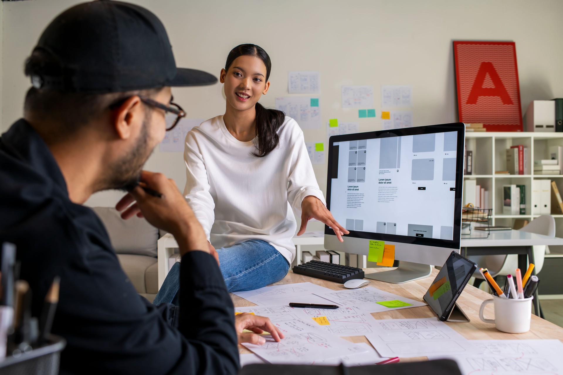UX UI designers discussing and brainstorming on wireframes for a website and mobile app prototype, surrounded by sketches of user flow and design tools, in the concept of website and mobile application design concept.